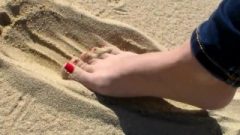 Red Toe Nails In The Beach Sand