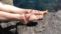 Painted Henna Feet Resting On The Rocks Near The Sea